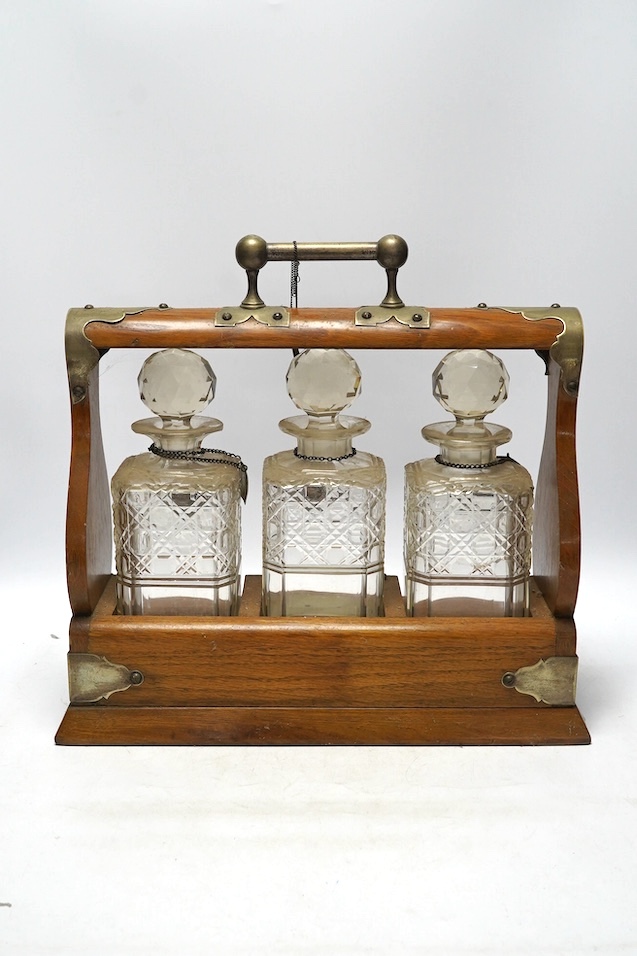 A Victorian oak three decanter tantalus with four spirit labels, and key, 37cm wide. Condition -fair